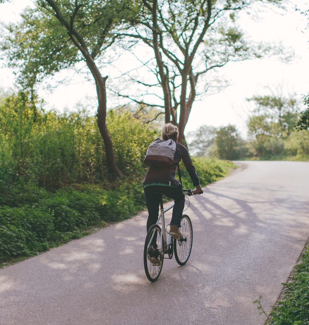 a person riding a bike on a path surrounded by trees